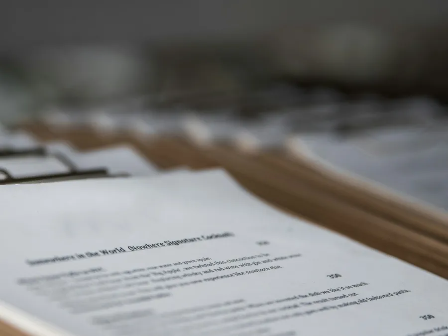 Printed terms of service, cottage keys and a bank card on a wooden table in a British holiday cottage, with a village street outside the window